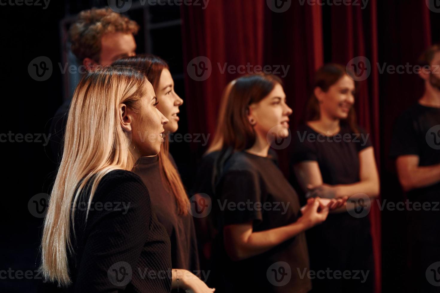 vue de côté. groupe d'acteurs vêtus de vêtements de couleur sombre en répétition au théâtre photo
