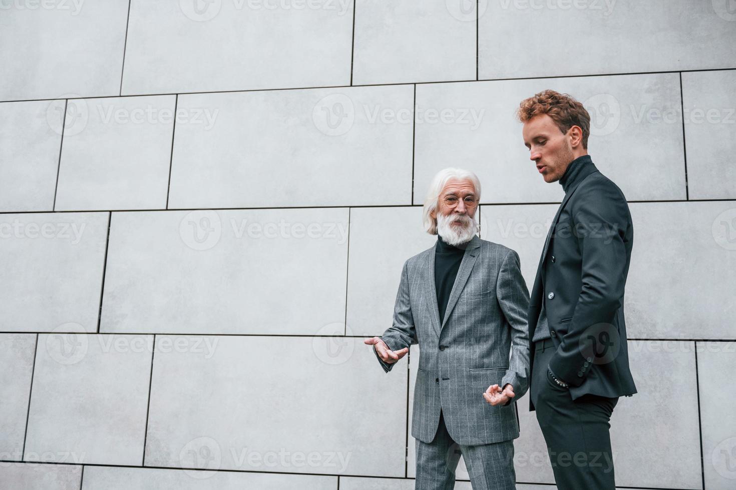 jeune homme avec un homme âgé dans des vêtements élégants est à l'extérieur ensemble. conception d'entreprise photo