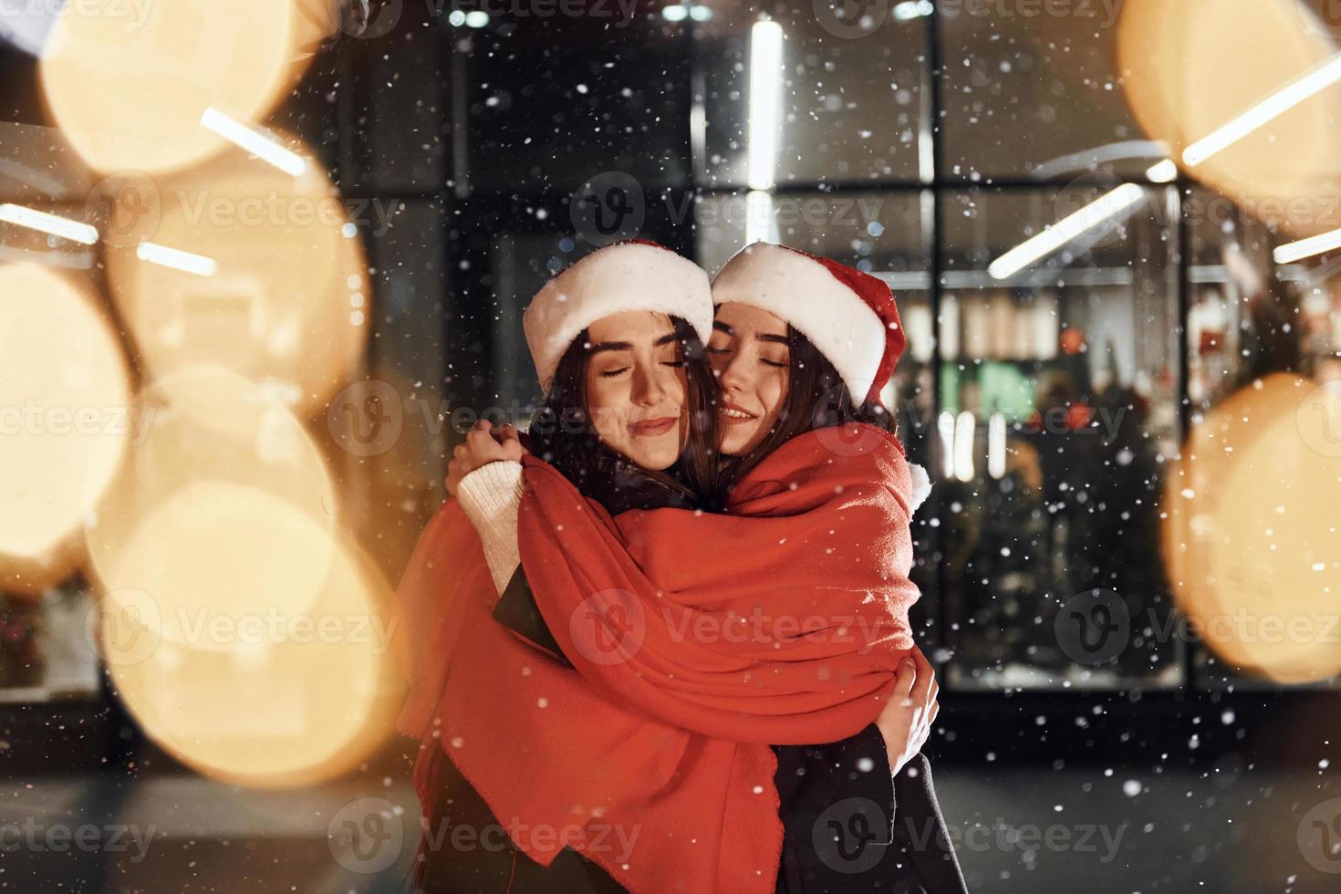 s'embrassant. les soeurs jumelles heureuses passent les vacances de noël ensemble à l'extérieur. conception du nouvel an photo