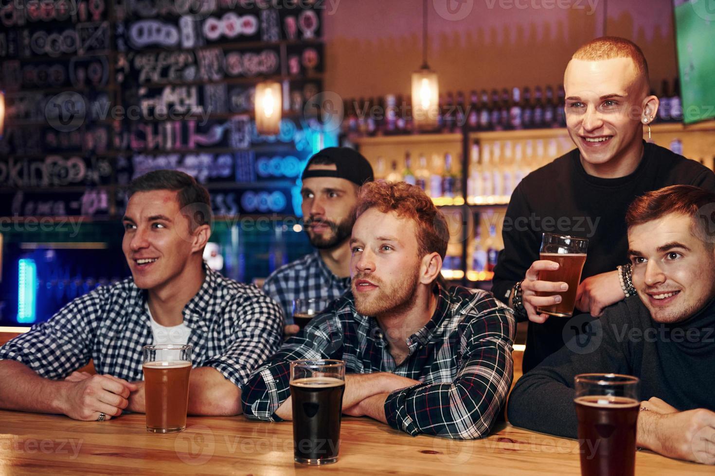 fans de football célébrant la victoire. groupe de personnes ensemble à l'intérieur dans le pub s'amuser le week-end photo