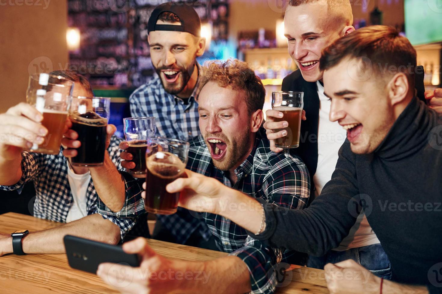 utilise le téléphone. groupe de personnes ensemble à l'intérieur dans le pub s'amuser le week-end photo