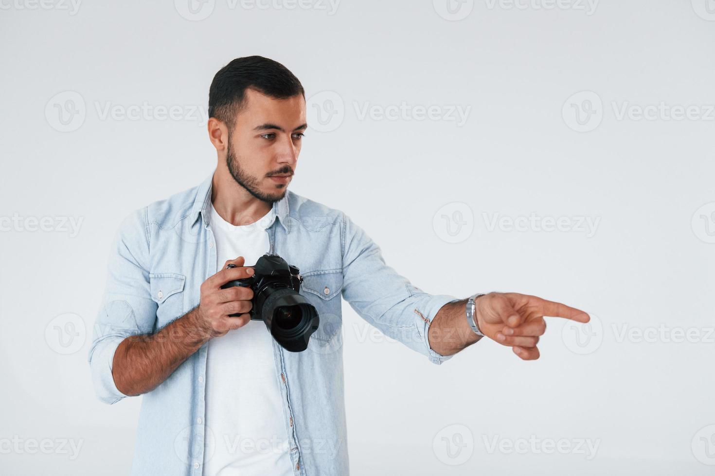 avec caméra professionnelle. jeune bel homme debout à l'intérieur sur fond blanc photo