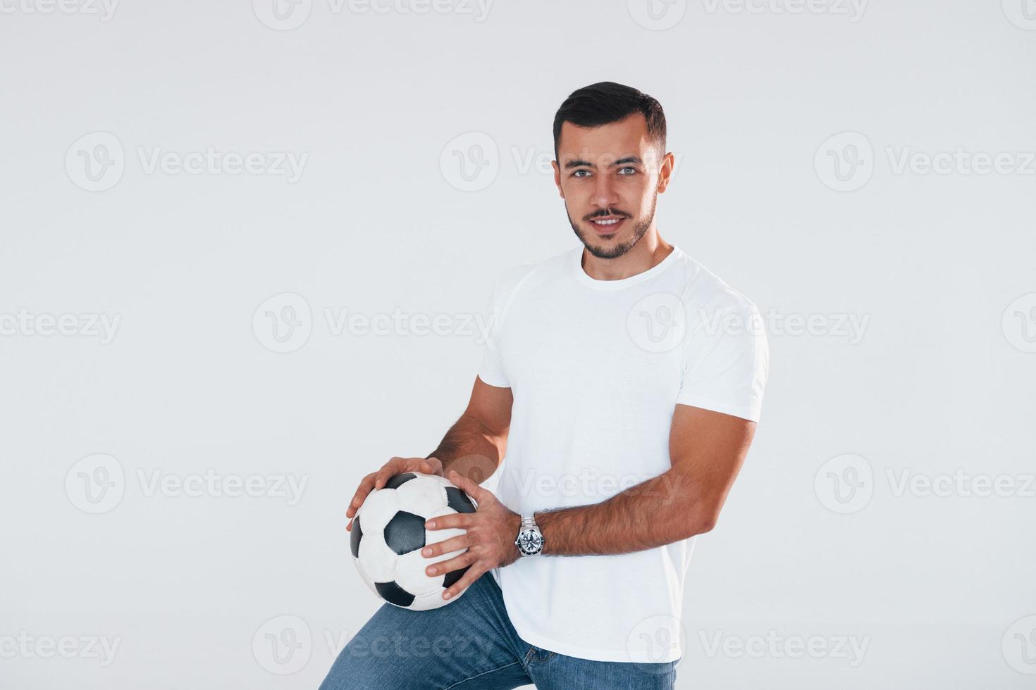 fan de football avec ballon de football. jeune bel homme debout à l'intérieur sur fond blanc photo