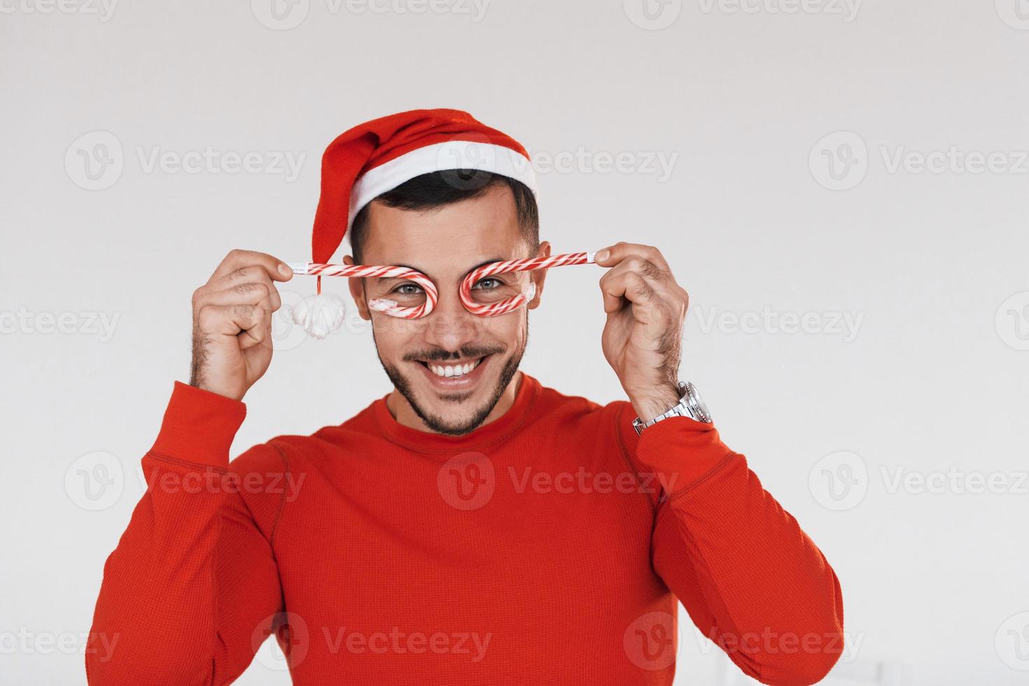 avec des bonbons. jeune bel homme en vêtements de nouvel an debout à l'intérieur sur fond blanc photo