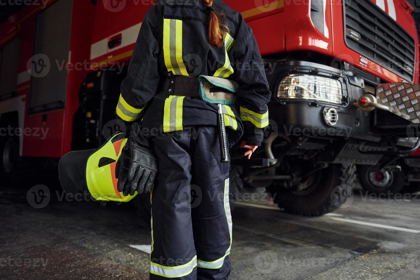 vue rapprochée. femme pompier en uniforme de protection debout près du camion photo