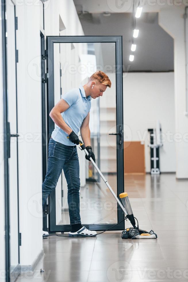 jeune homme travaille dans le bureau moderne. utilise un aspirateur photo