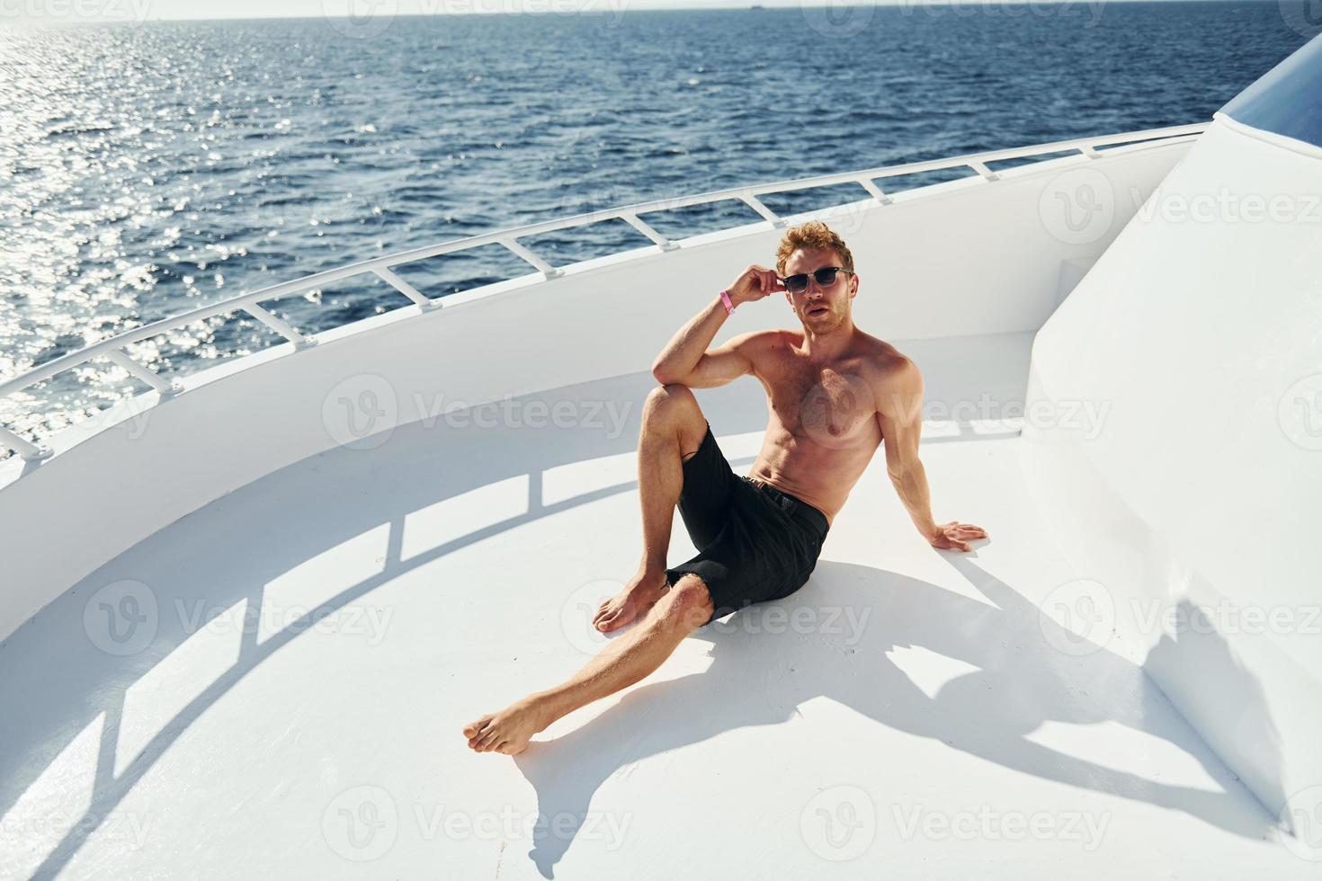 en lunettes de soleil. jeune touriste masculin est sur le yacht sur la mer. conception de vacances photo