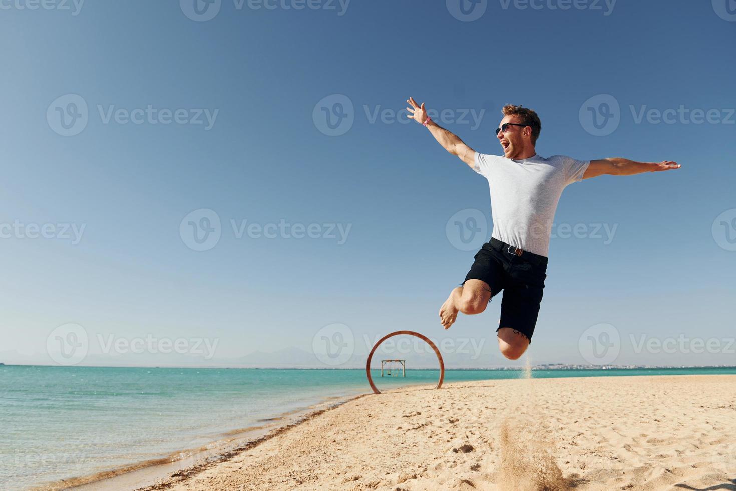 s'amuser. jeune homme européen passe des vacances et profite de temps libre sur la plage de la mer photo