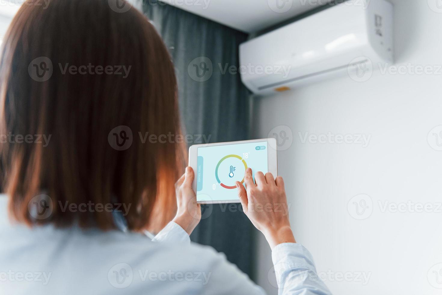 vue arrière d'une femme qui contrôle à l'intérieur la technologie de la maison intelligente photo