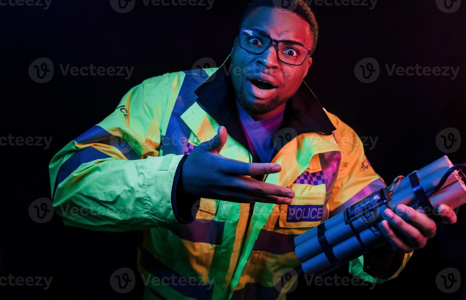 policier avec bombe. éclairage néon futuriste. jeune homme afro-américain dans le studio photo