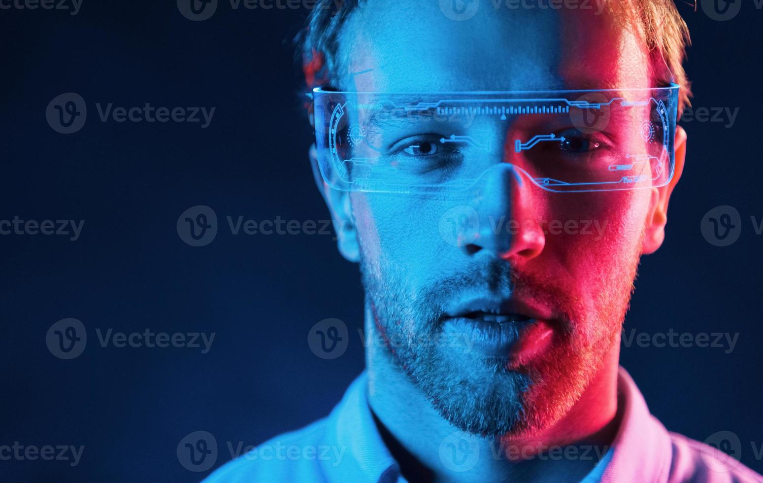 dans des verres avec affichage. éclairage au néon. jeune homme européen est dans le studio sombre photo