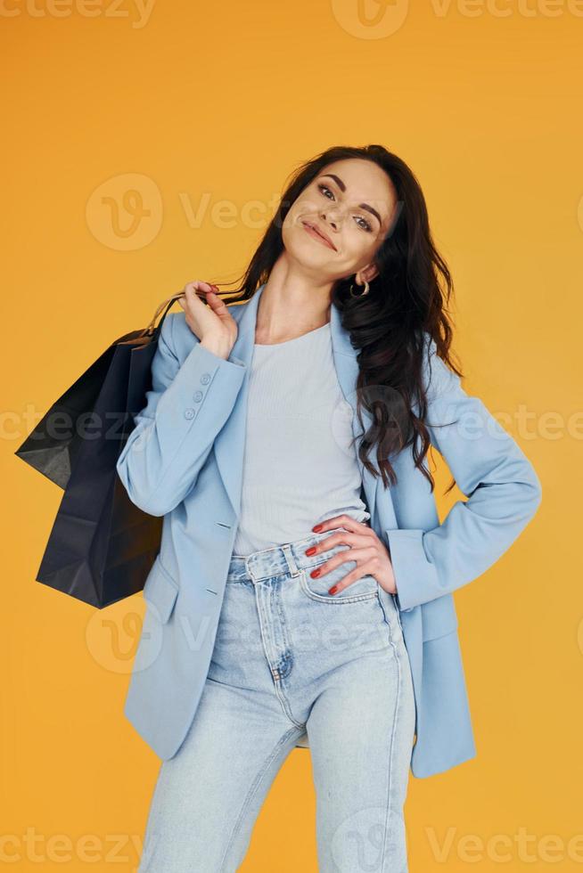 avec des sacs à provisions. femme européenne dans des vêtements élégants à la mode pose à l'intérieur photo