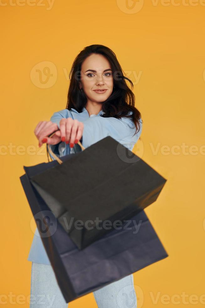 avec des sacs à provisions. femme européenne dans des vêtements élégants à la mode pose à l'intérieur photo