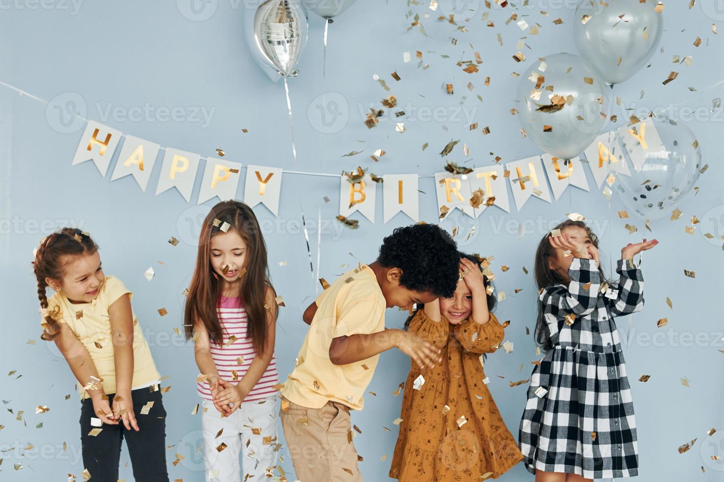 ballons et confettis. les enfants célébrant la fête d'anniversaire à l'intérieur s'amusent ensemble photo