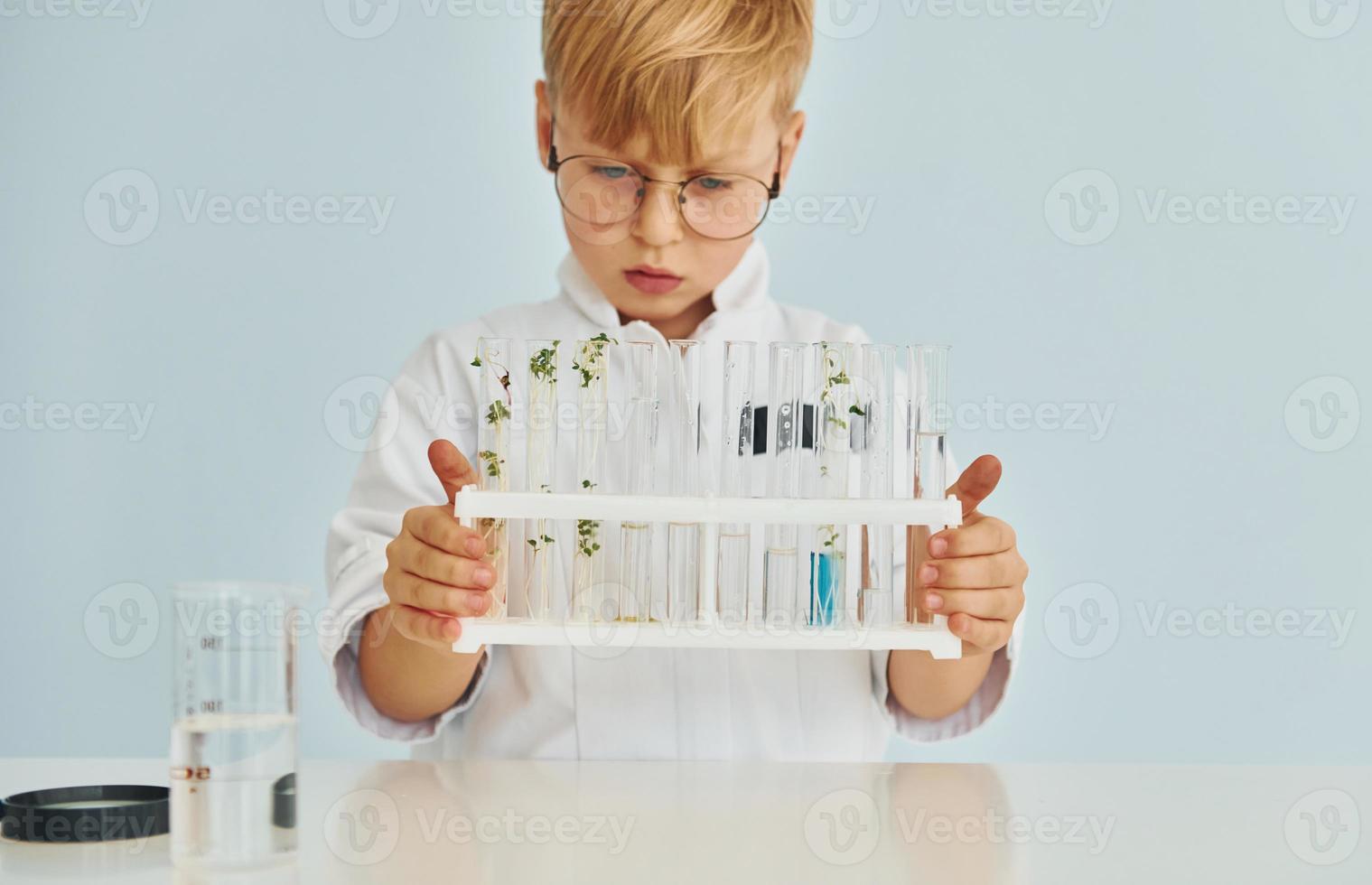 utilise des éprouvettes. petit garçon en manteau jouant un scientifique en laboratoire à l'aide d'équipement photo