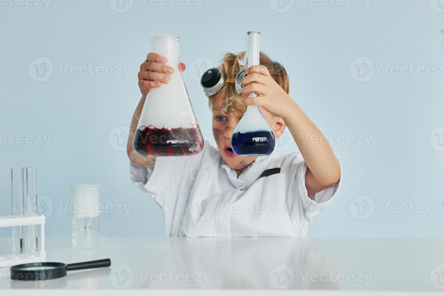 petit garçon en manteau jouant un scientifique en laboratoire à l'aide d'équipement photo