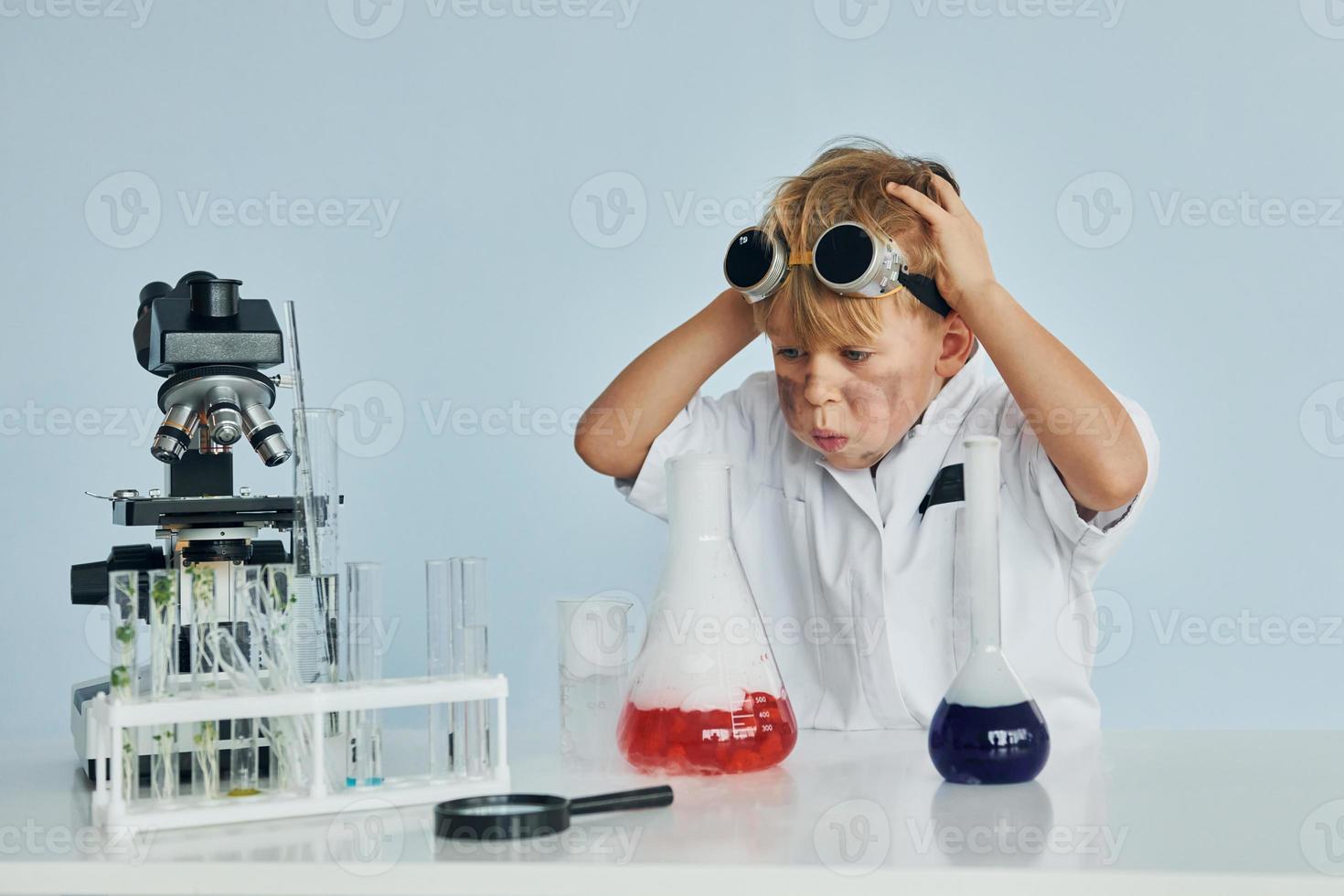 petit garçon en manteau jouant un scientifique en laboratoire à l'aide d'équipement photo