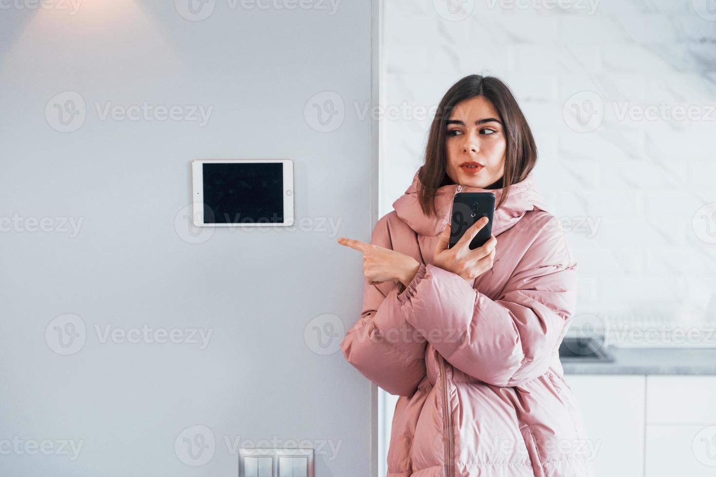 Contrôle du climat. la jeune femme est à l'intérieur dans la chambre de la maison intelligente pendant la journée photo