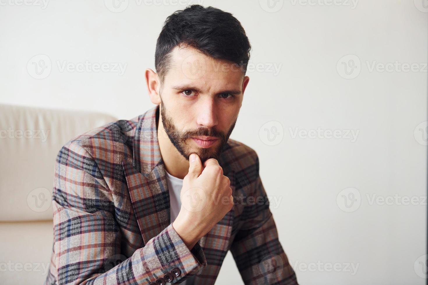 est assis sur la chaise. jeune homme d'affaires élégant en costume à l'intérieur. conception du succès photo