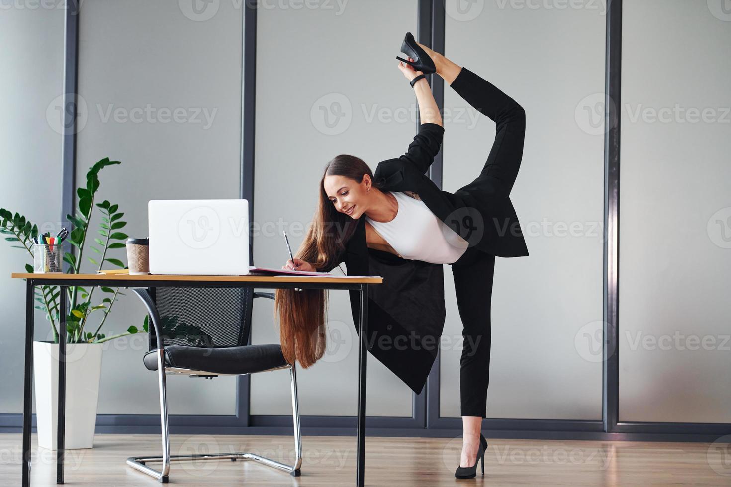 avec ordinateur portable. jeune femme adulte en vêtements formels est à l'intérieur au bureau photo