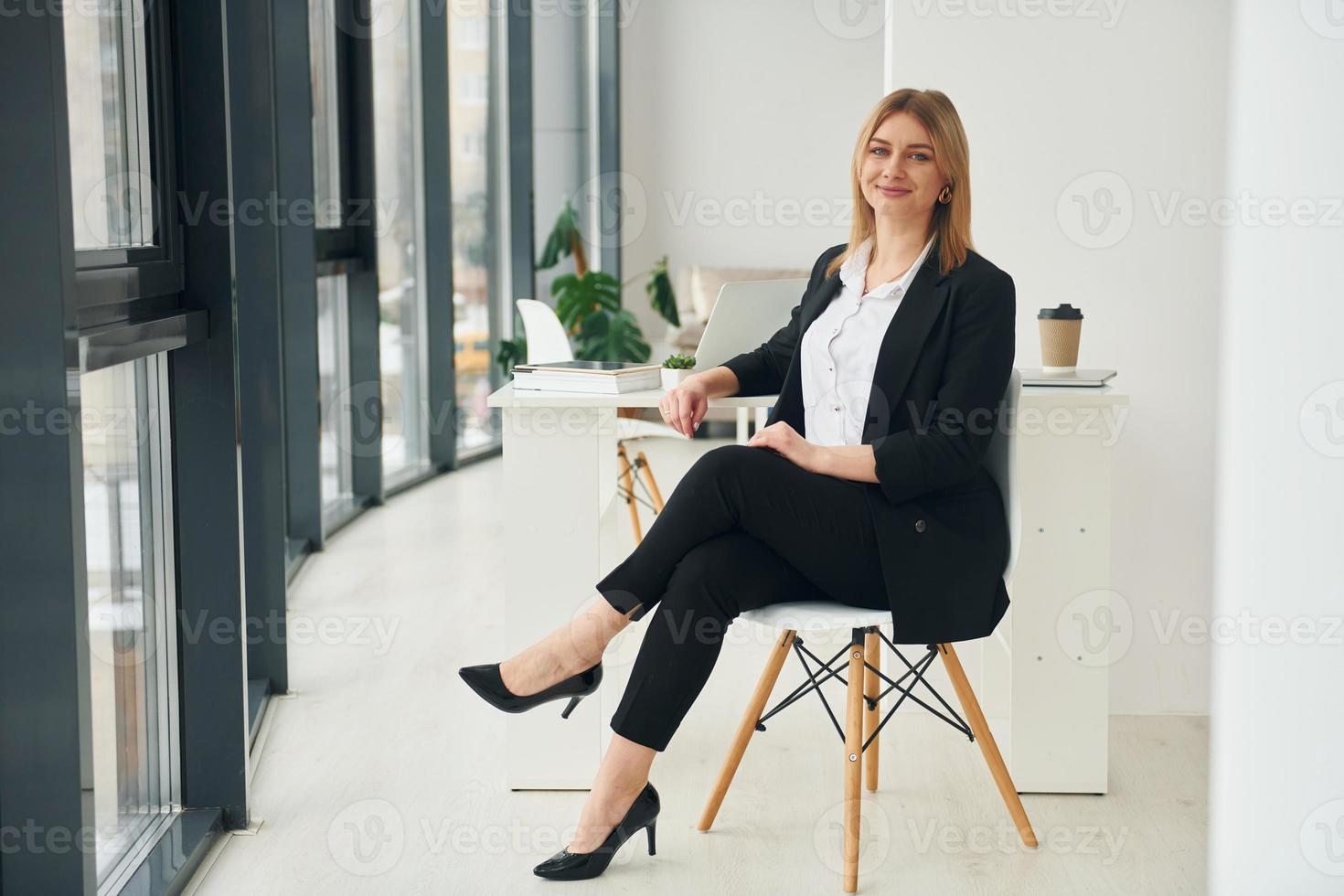 femme en vêtements formels est assise sur la chaise à l'intérieur dans le bureau moderne pendant la journée photo