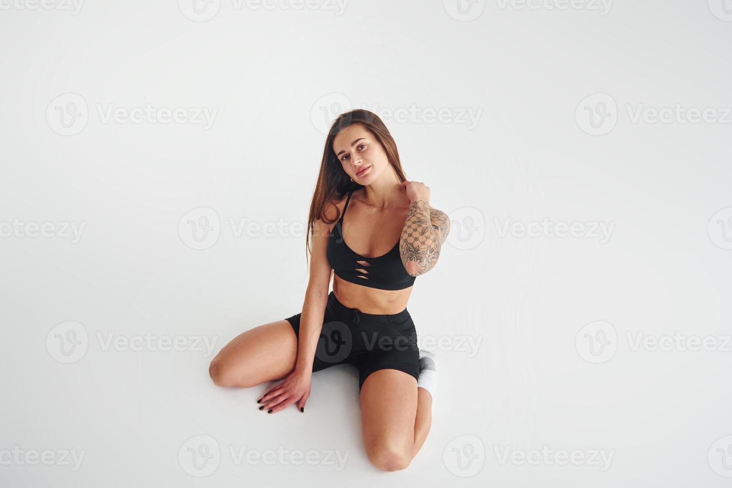 est assis sur le sol. belle femme sportive séduisante avec un corps sexy pose en studio photo