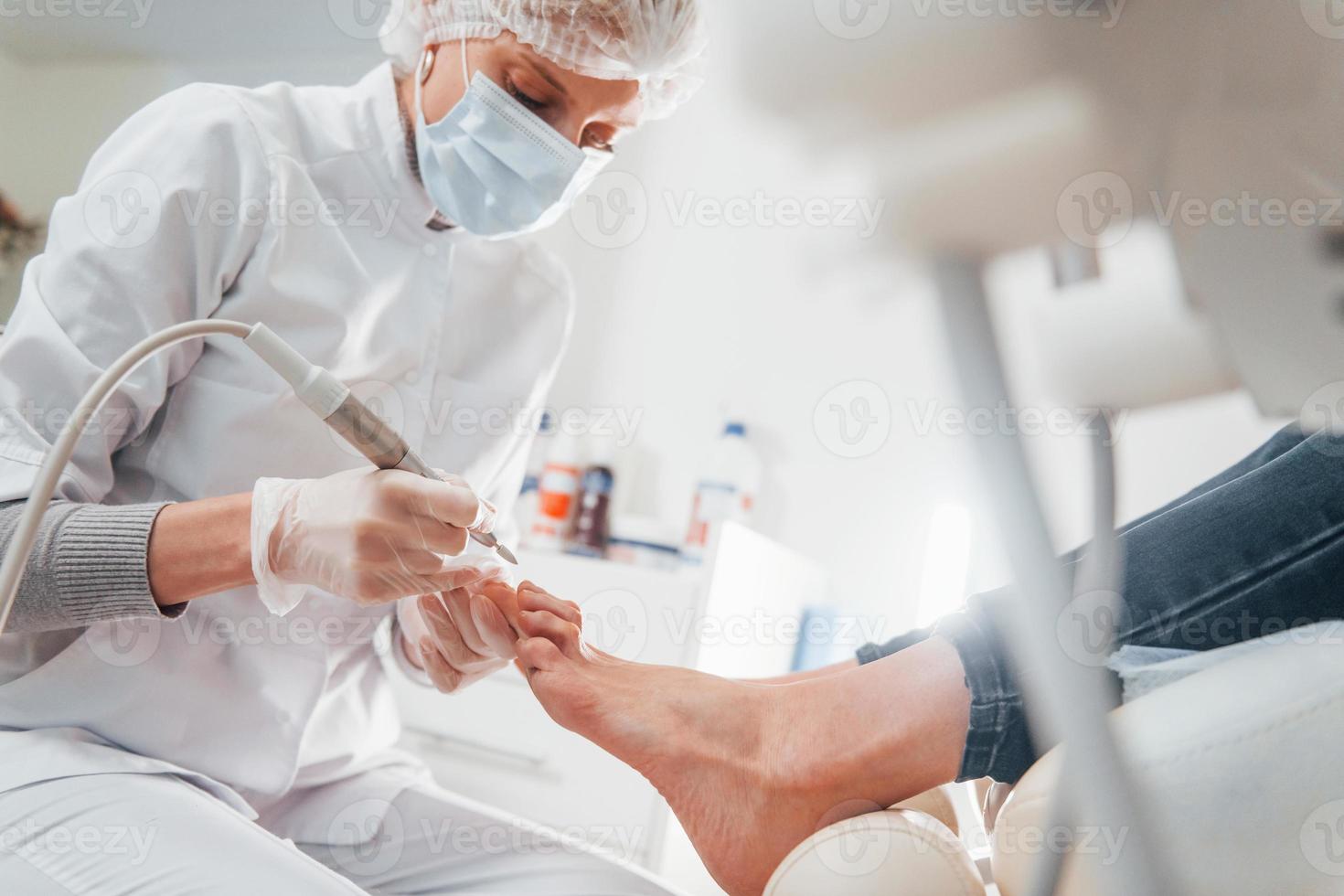 femme allongée et opérée des pieds par un professionnel de la clinique photo