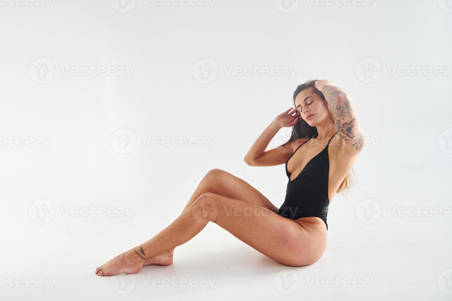 est assis sur le sol. belle femme sportive séduisante avec un corps sexy pose en studio photo