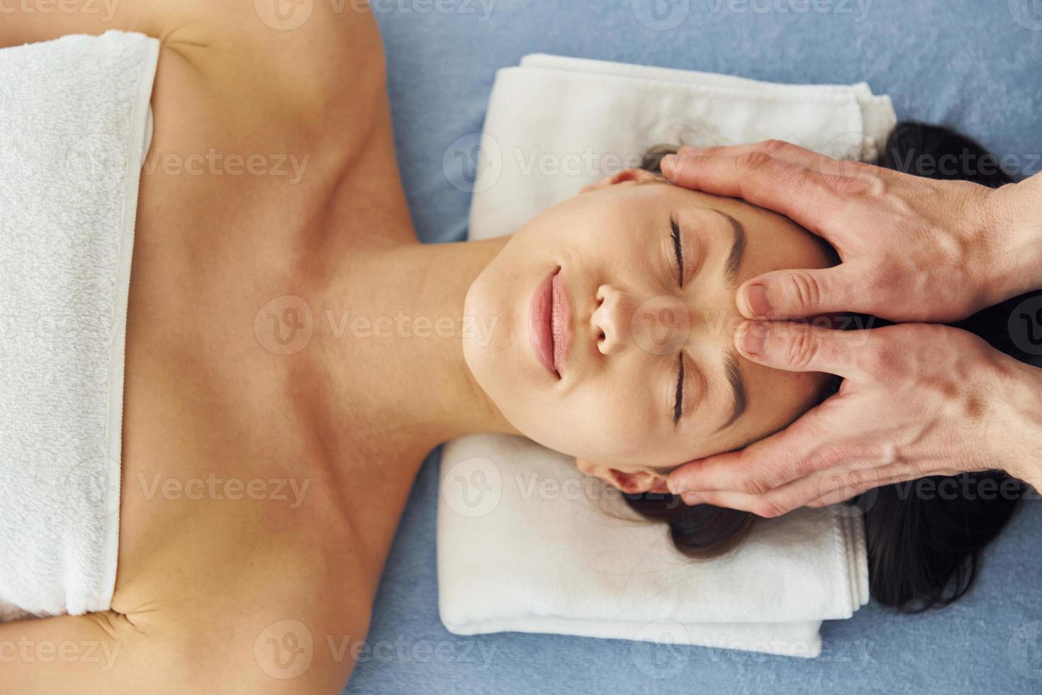 massage crânien. une jeune femme est allongée quand un homme lui fait une procédure au spa photo