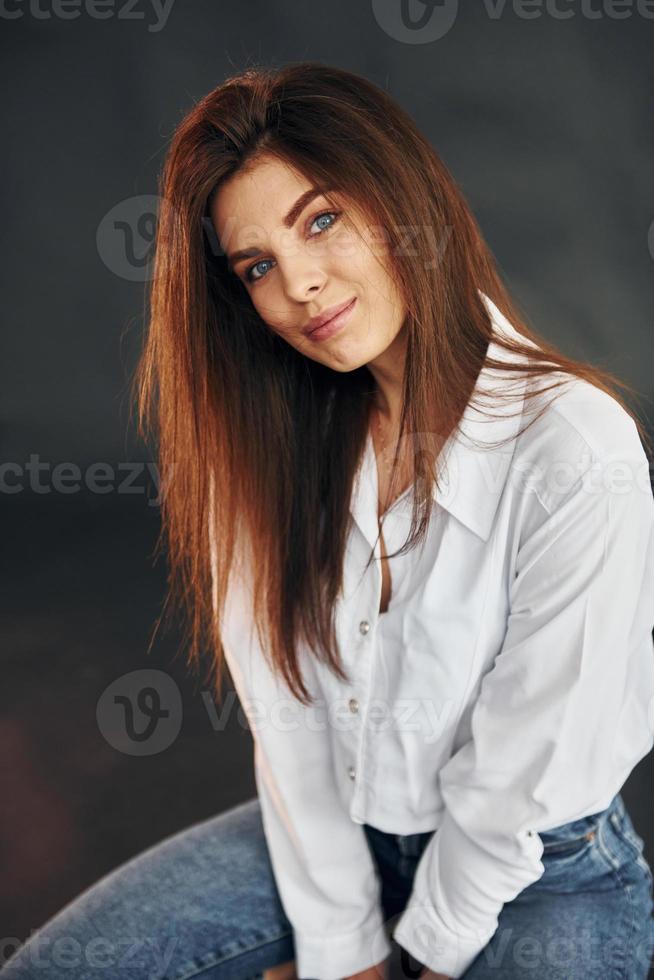 en chemise blanche et jean bleu. belle jeune femme pose pour la caméra dans le studio photo