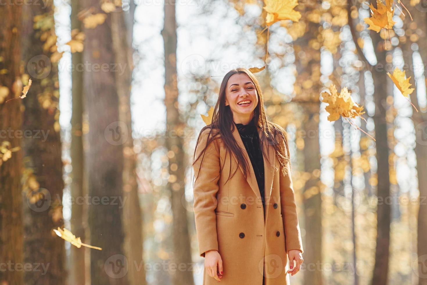 avoir de la bonne humeur. femme en manteau se promener dans la forêt d'automne photo