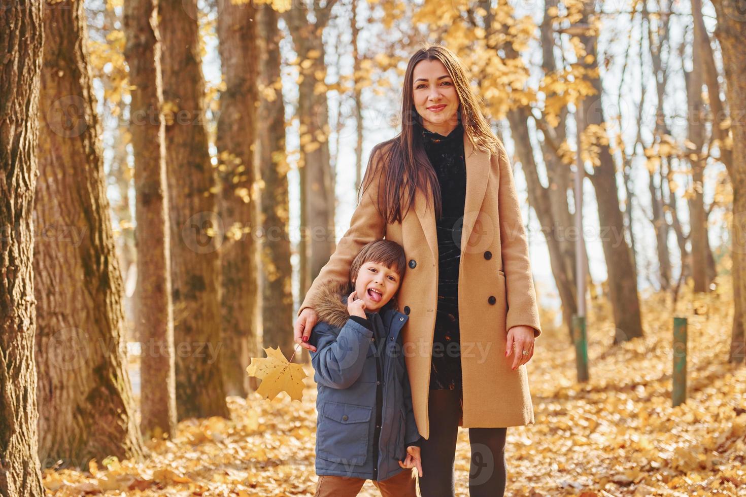 femme et garçon joyeux. mère avec son fils s'amuse dehors dans la forêt d'automne photo