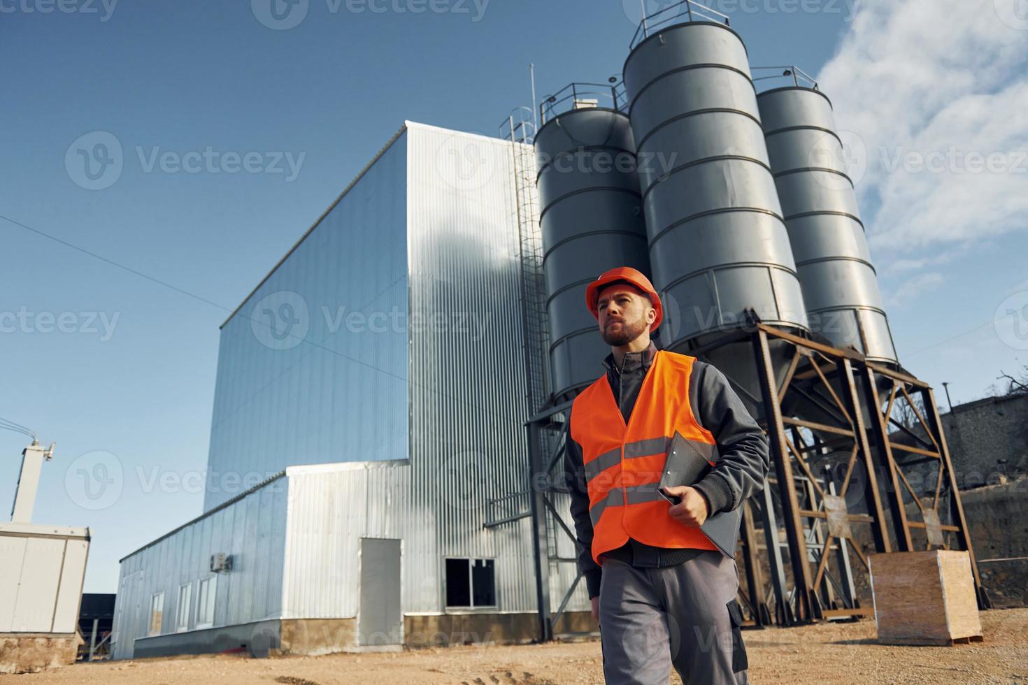 extérieur du bâtiment. ouvrier du bâtiment en uniforme est à l'extérieur près de l'usine photo