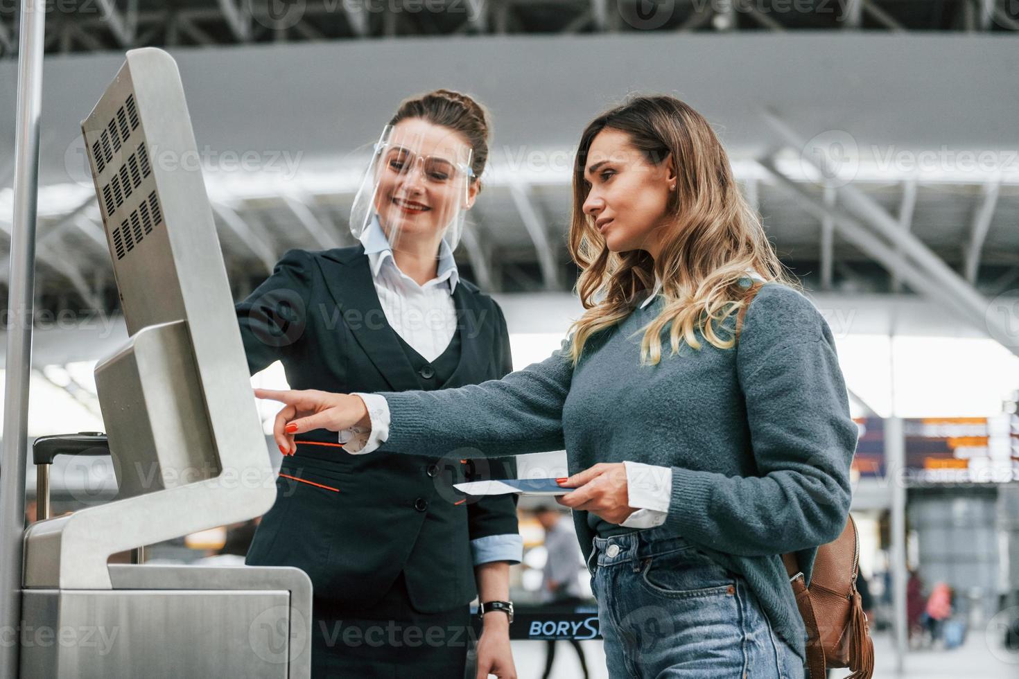 employé aidant à utiliser le terminal. jeune femme touriste est à l'aéroport pendant la journée photo