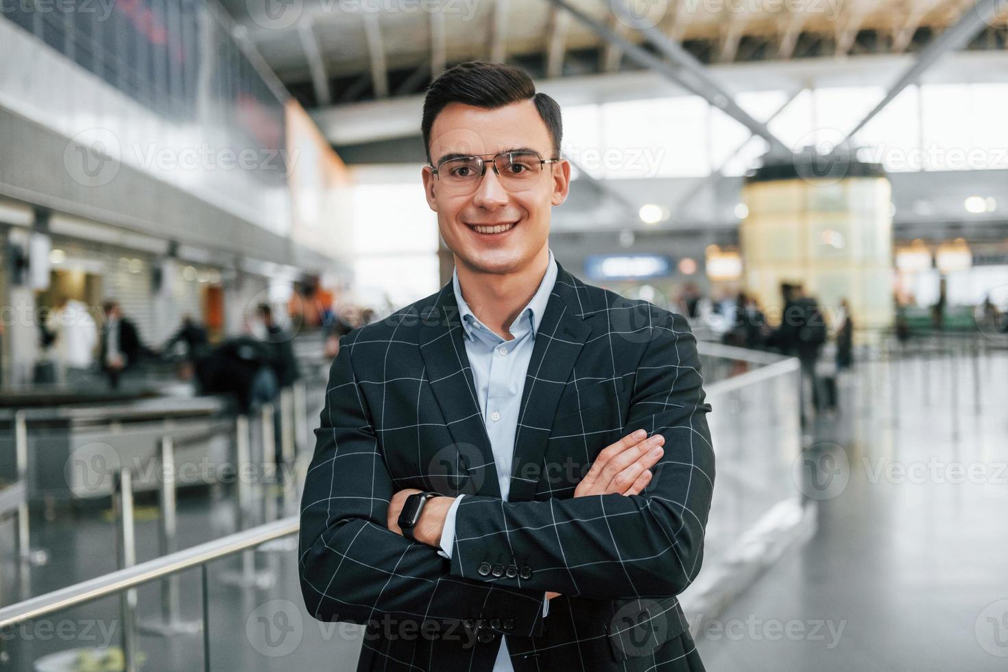 avec les bras croisés. jeune homme d'affaires en vêtements formels est à l'aéroport pendant la journée photo