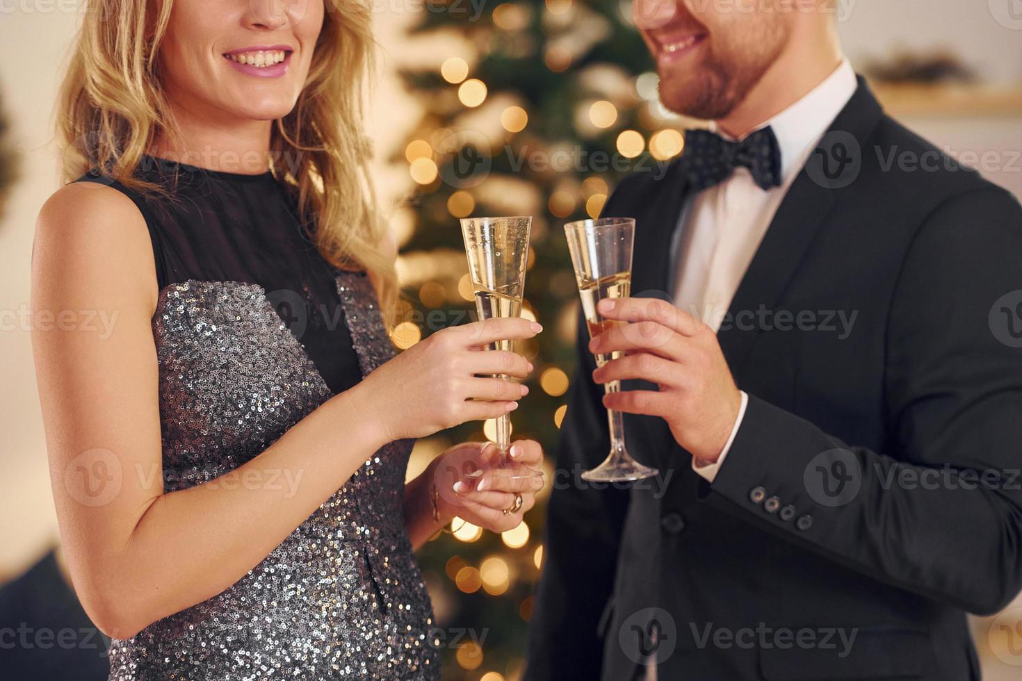 applaudir avec des verres d'alcool. un couple heureux organise une fête du nouvel an à l'intérieur ensemble photo