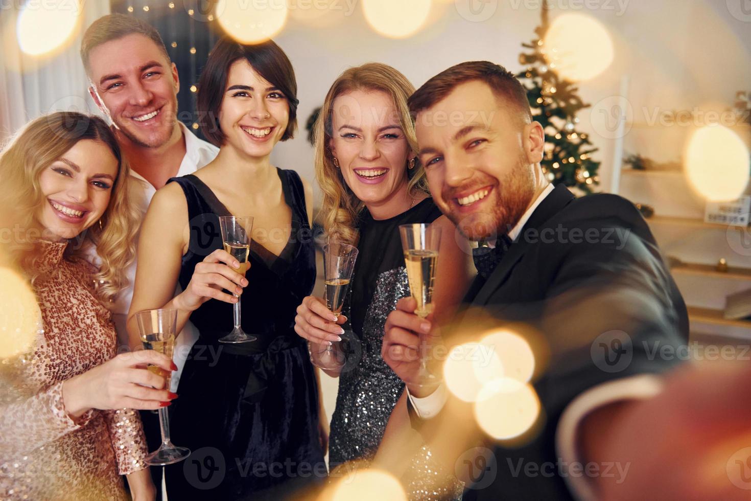 tenant le téléphone. un groupe de personnes organise une fête du nouvel an à l'intérieur photo