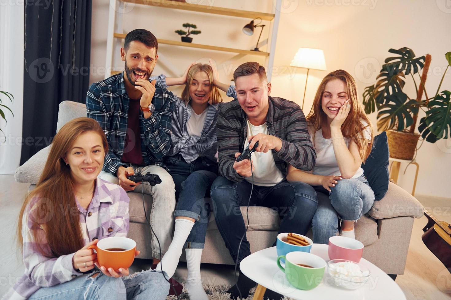 jouer à un jeu vidéo. un groupe d'amis fait la fête ensemble à l'intérieur photo