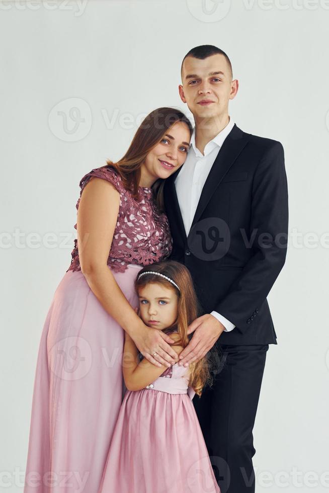 un couple heureux avec une petite fille se tient debout dans le studio photo