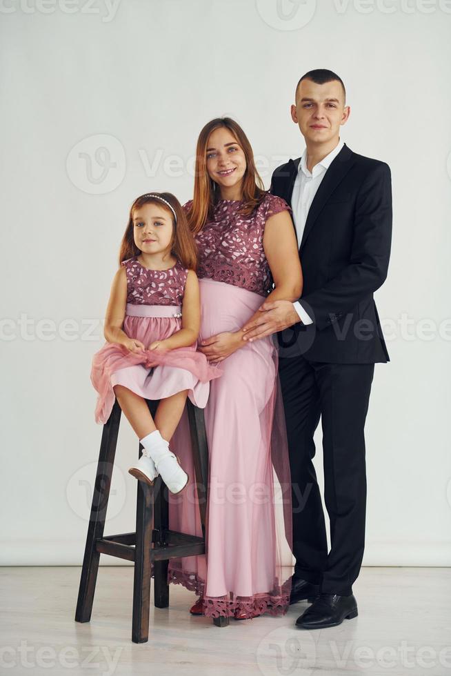 fille est assise sur la chaise. un couple heureux avec une petite fille se tient debout dans le studio photo