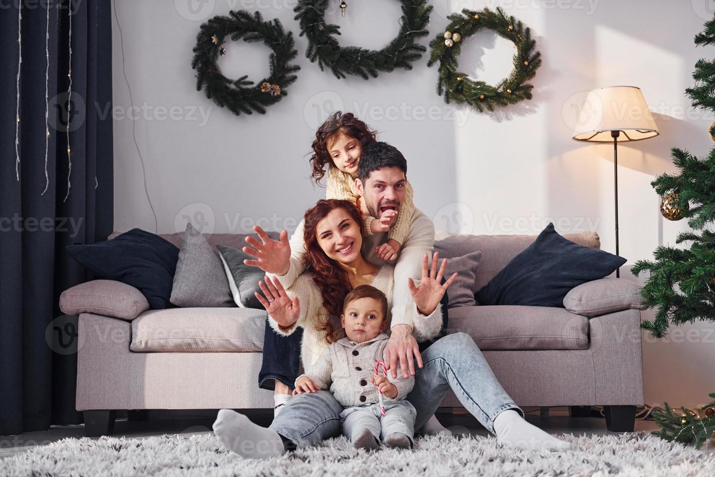 assis près du canapé. famille célébrant le nouvel an avec leurs enfants à la maison photo