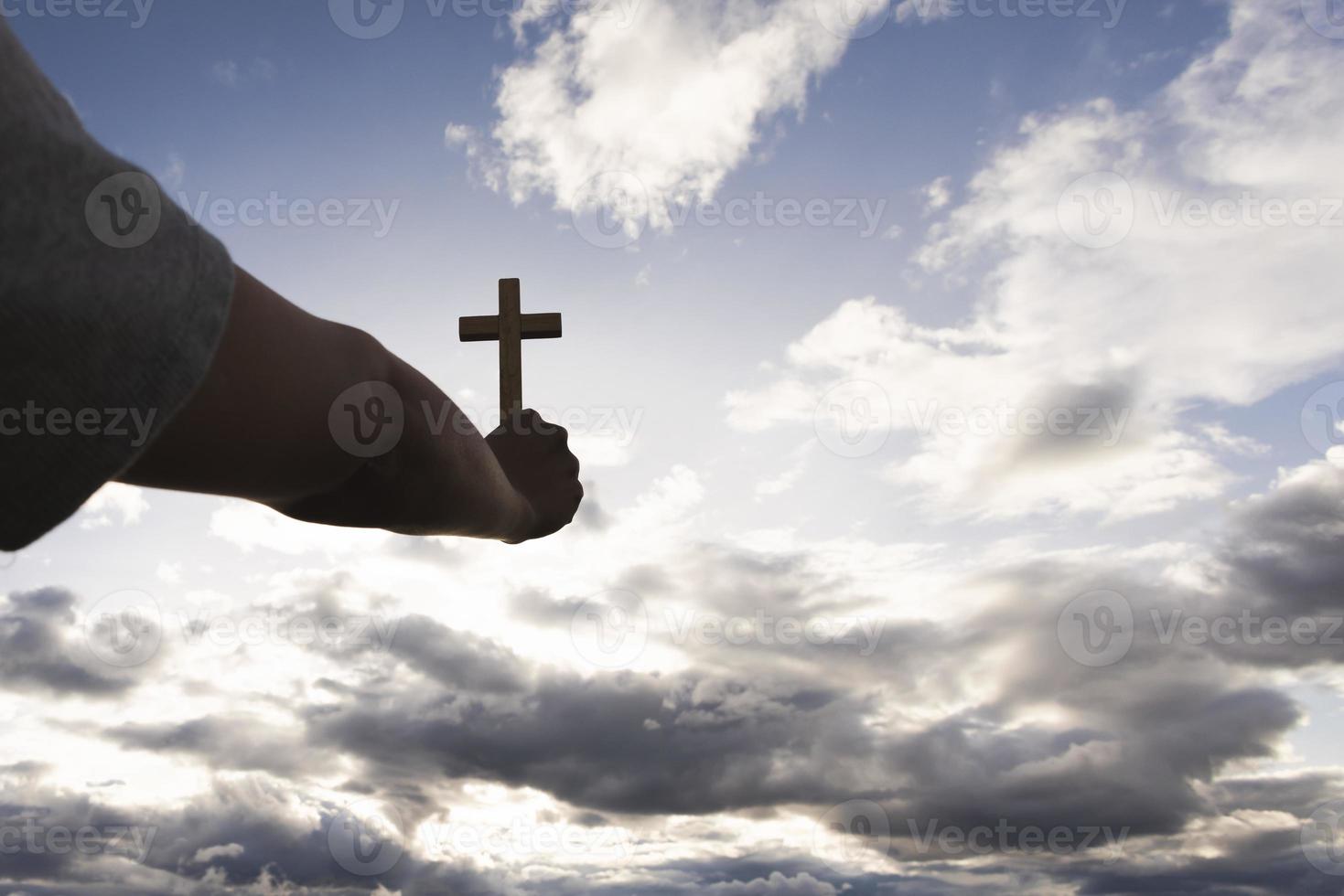 main humaine tenant une croix dans le ciel. symbole de la foi en la prière de Dieu. délivrance. prière. conception chrétienne. photo