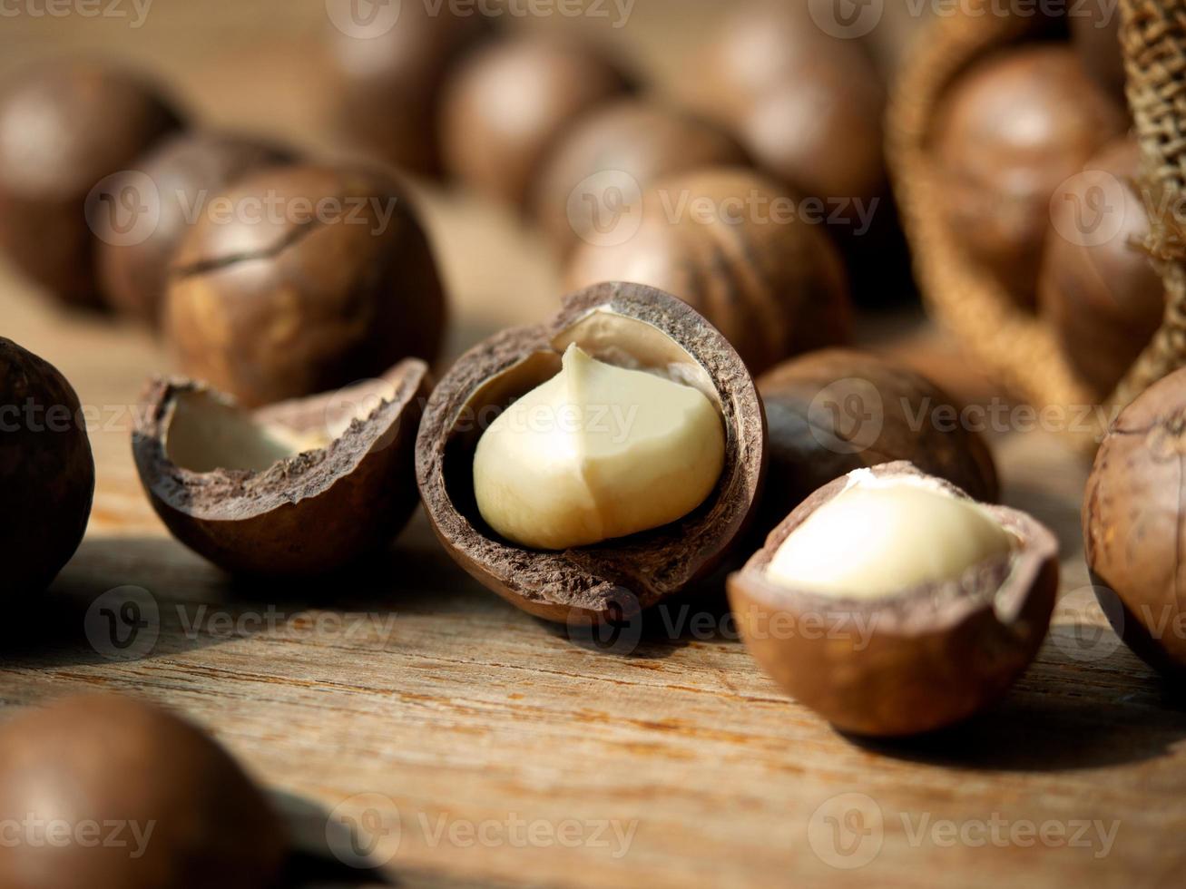 noix de macadamia rôties sur une table en bois pour une collation saine ou un concept de nourriture végétalienne. photo