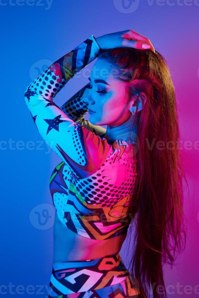 femme confiante dans des vêtements colorés debout dans le studio avec néon photo