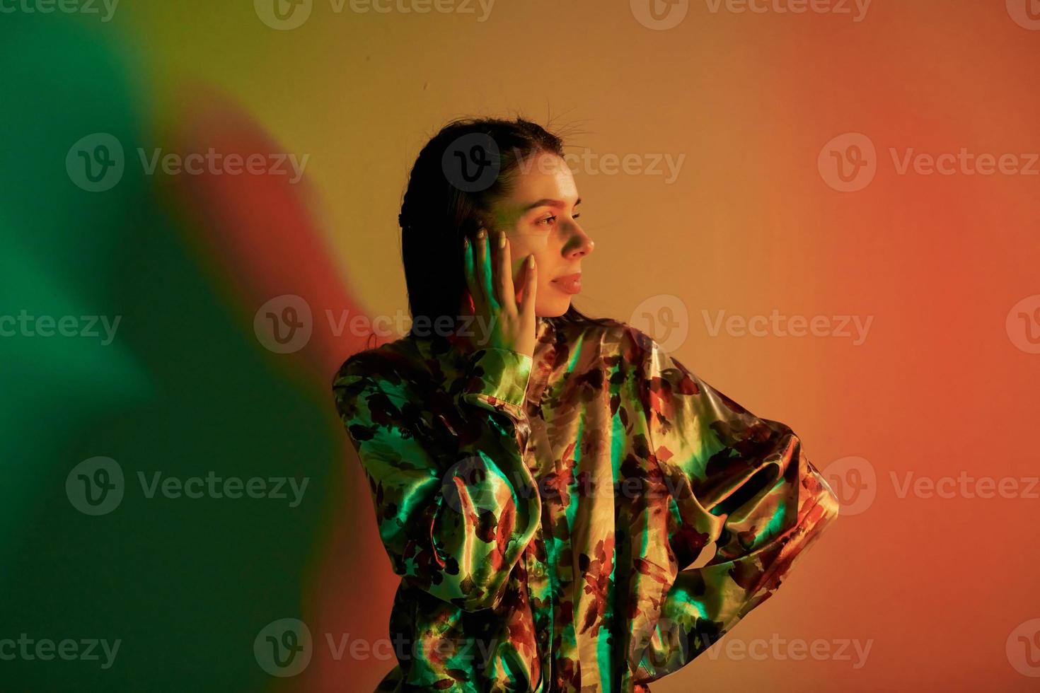 posant pour la caméra. jeune femme à la mode debout dans le studio avec néon photo