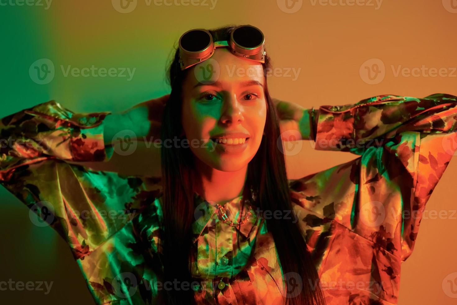 lunettes rétro. jeune femme à la mode debout dans le studio avec néon photo