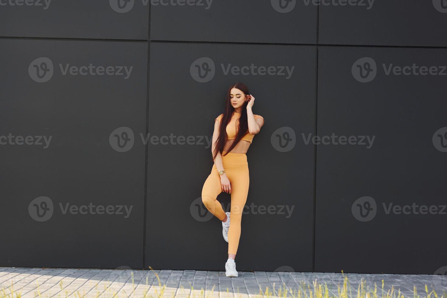 posant pour un appareil photo. jeune femme en vêtements de sport a une séance de fitness en plein air photo