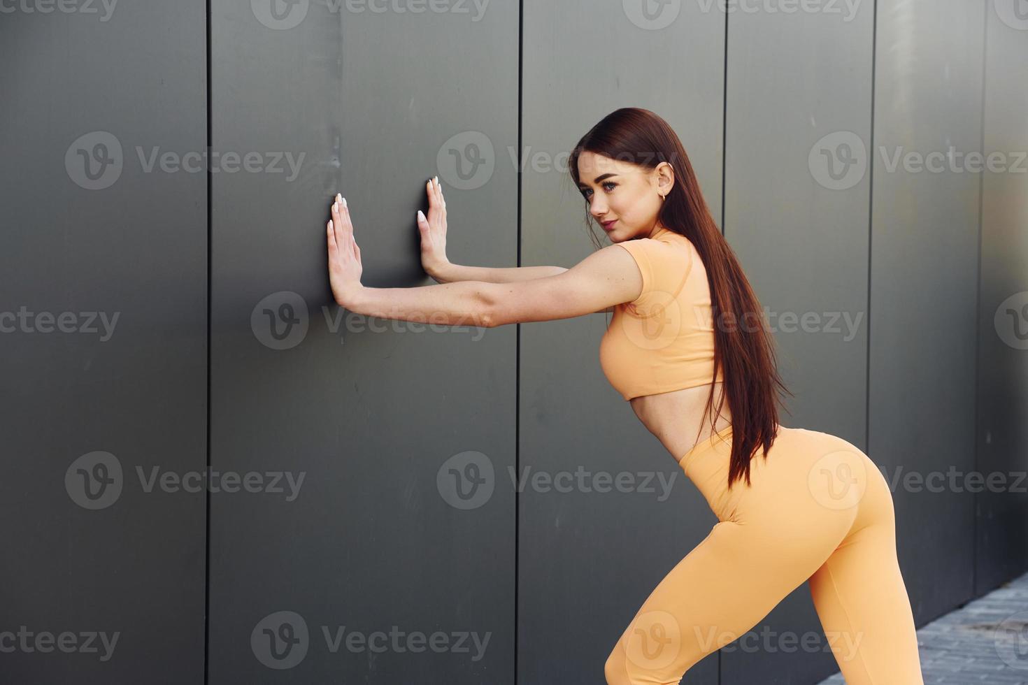 vue de côté. jeune femme en vêtements de sport a une séance de fitness en plein air photo