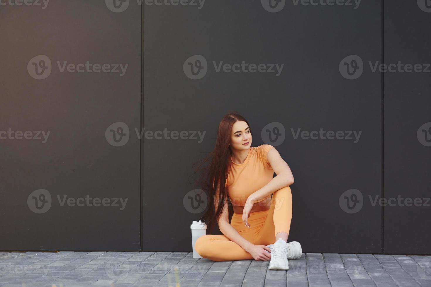 est assis sur le sol. jeune femme en vêtements de sport a une séance de fitness à l'extérieur photo