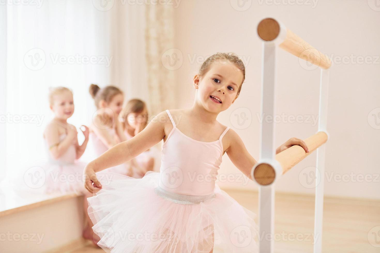 s'appuyant sur le support en bois. petites ballerines se préparant pour la performance photo